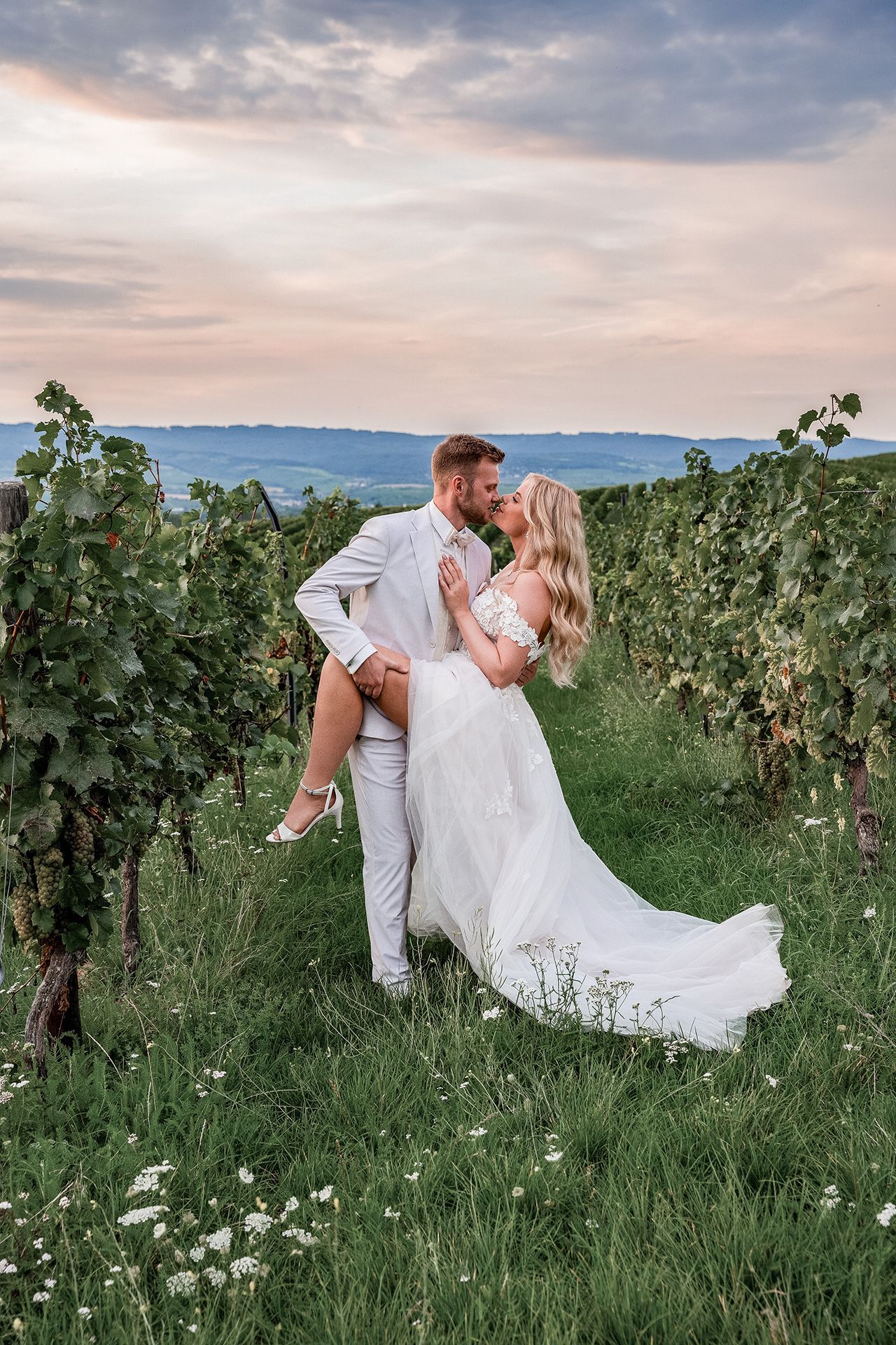 Brautpaar in Weinbergen in Ingelheim zur golden Hour, er zieht ihr Bein zu sich, sie küssen sich innig