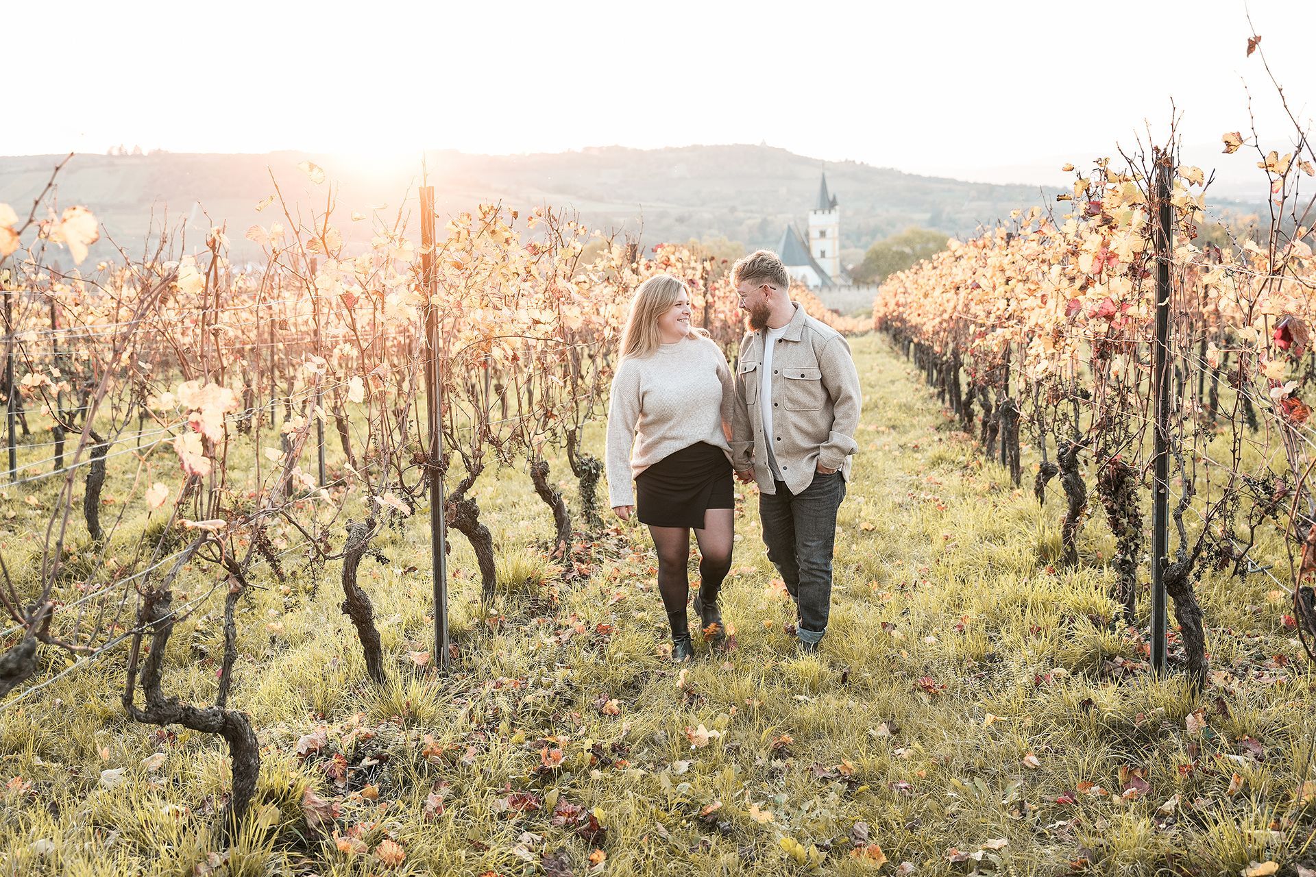 Paar läuft Arm in Arm zwischen den Weinreben in Ingelheim, schaut sich verliebt an