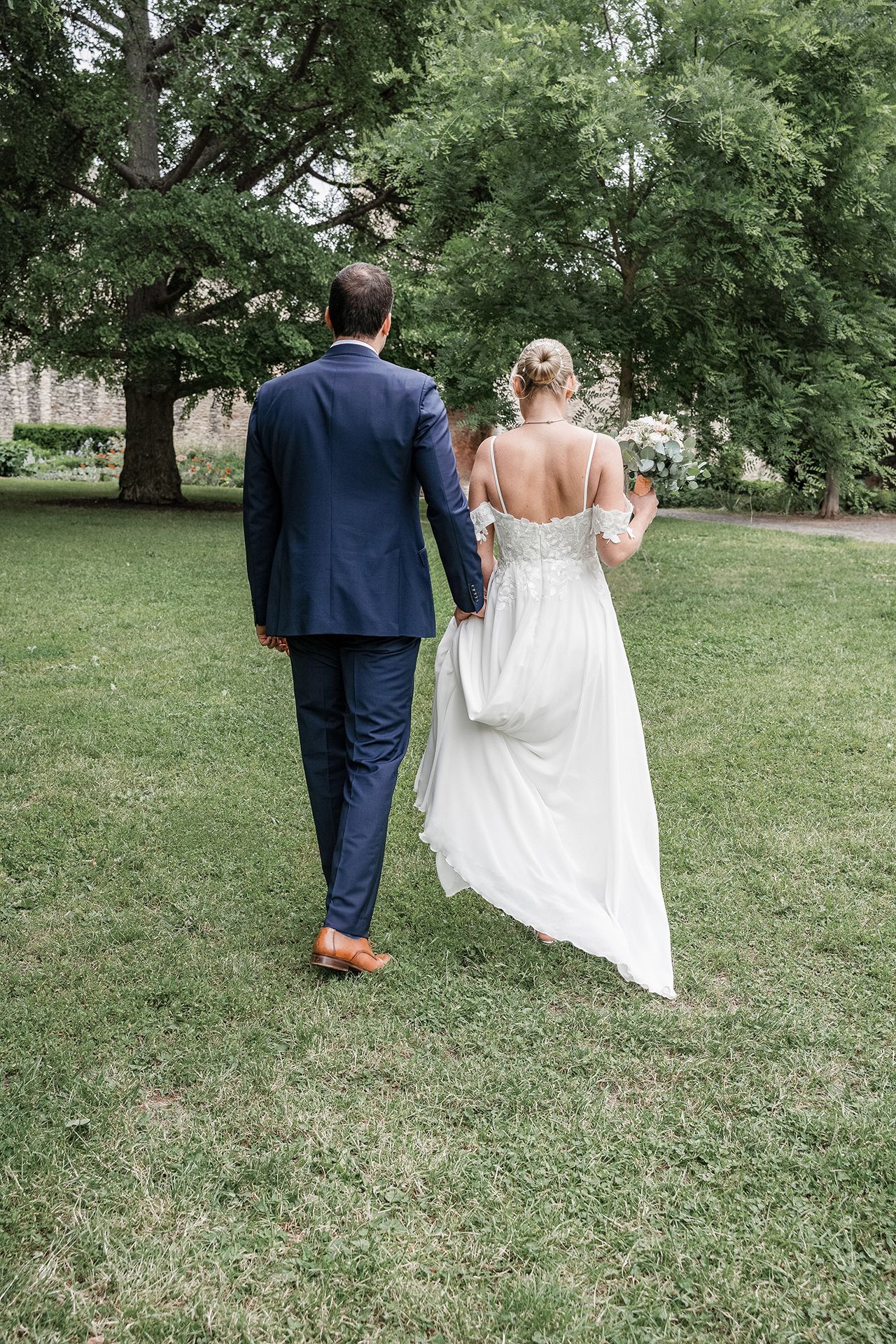 Brautpaar geht von der Kamera weg, Hand in Hand für Hochzeitsfotos