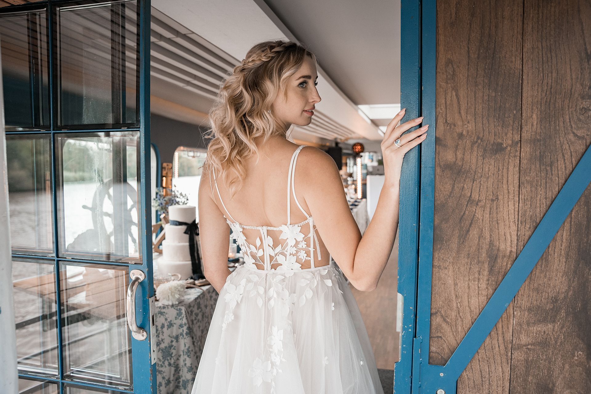 Braut steht in der offenen Schiffstür und schaut zur Seite für Hochzeitsfotos