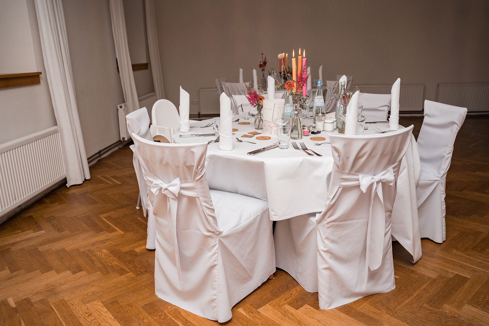 Battenheimer Hof indoor - Weiß eingedeckter Hochzeitstisch mit pinken und orangen Dekoelementen