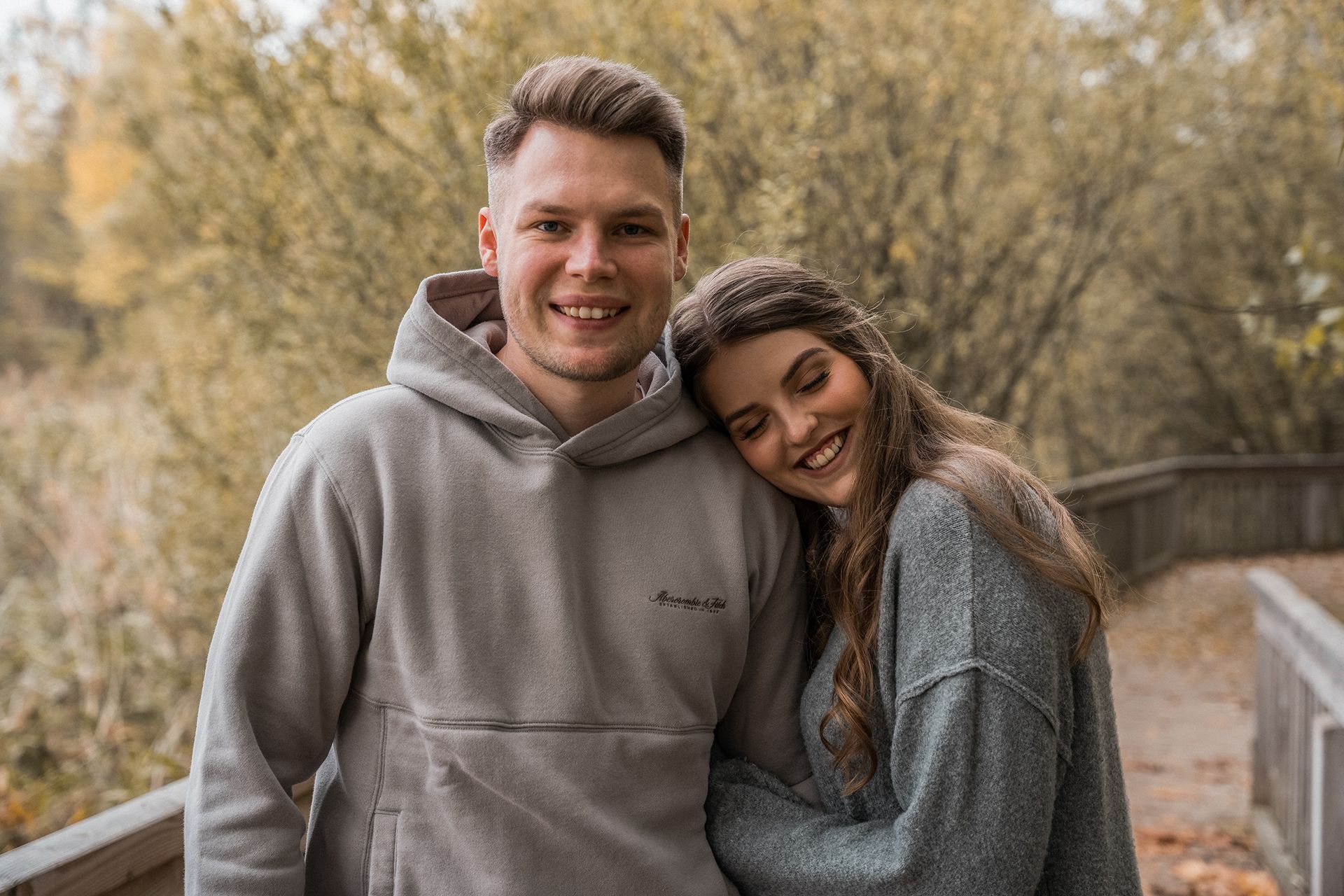 Paarshooting Mainz, Paar auf Holzsteg, Frau lehnt Kopf an seine Schulter, Mann lacht in die Kamera