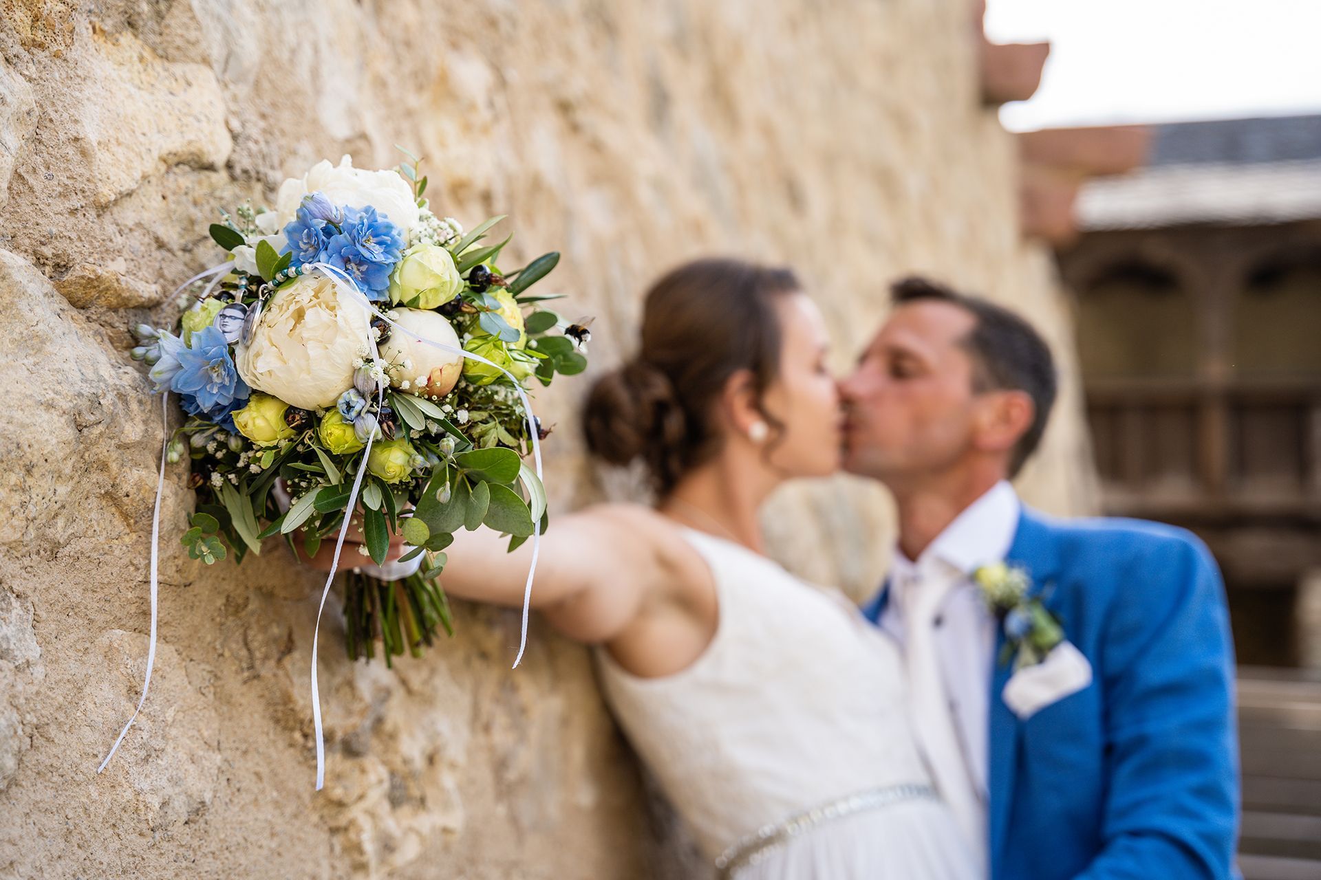 Hochzeitsfotograf Eltville, Brautpaar küsst sich an den Mauern der Kurfürstlichen Burg, Brautstrauß im Fokus
