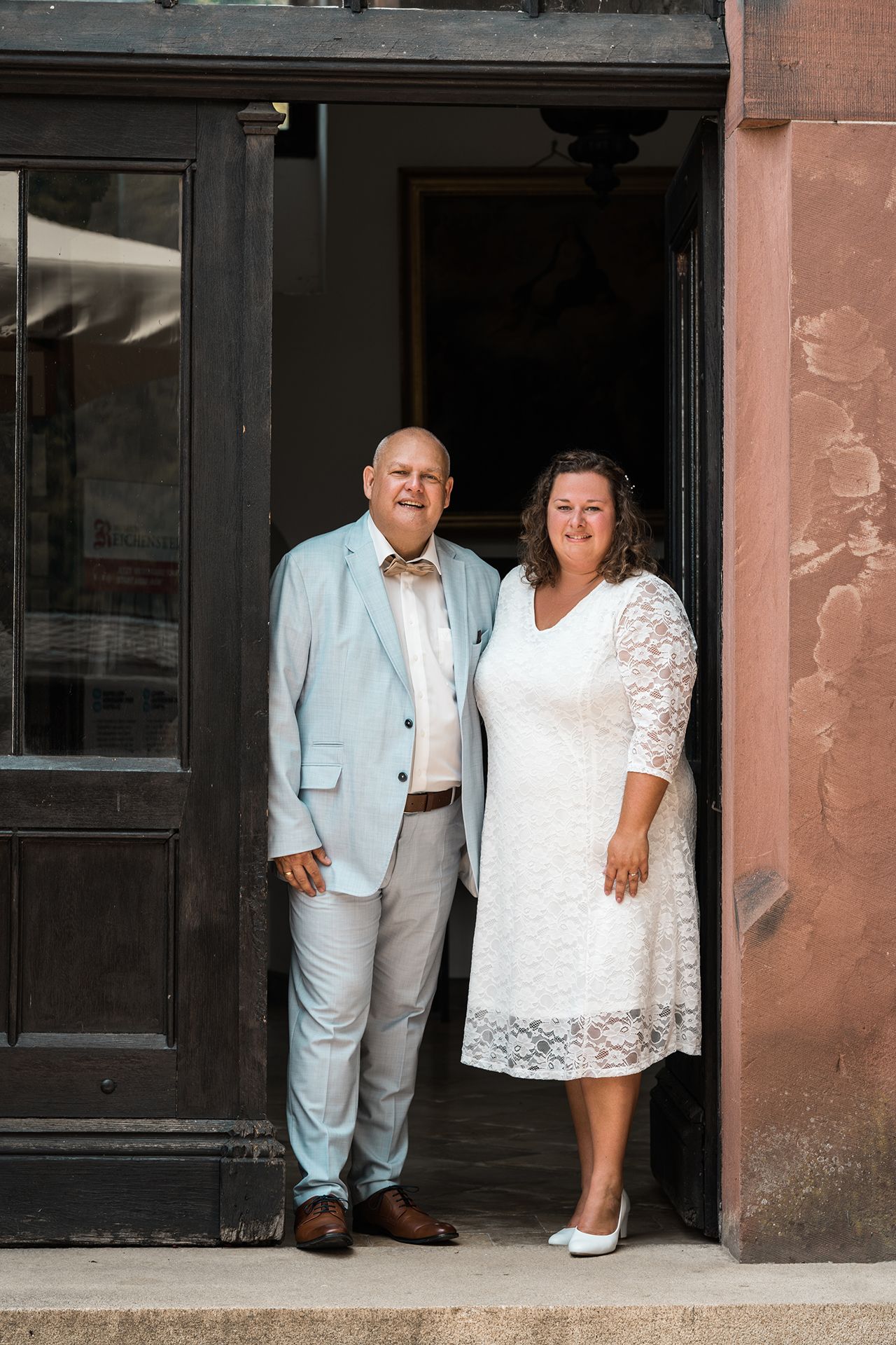 Hochzeitsfotograf Burg Reichenstein, Brautpaar lächelnd in einer Tür für einzigartige Hochzeitsfotos
