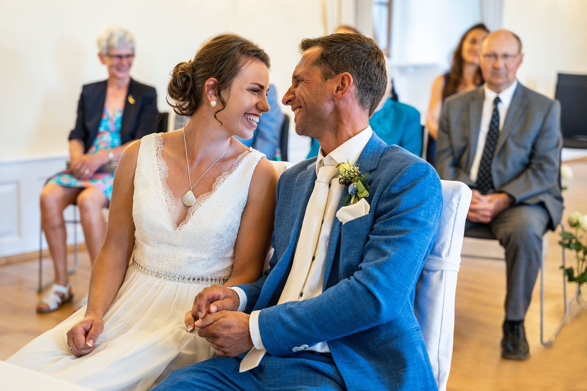 Brautpaar im Standesamt Eltville, Braut lächelt zu Gästen, Bräutigam schaut zu ihr