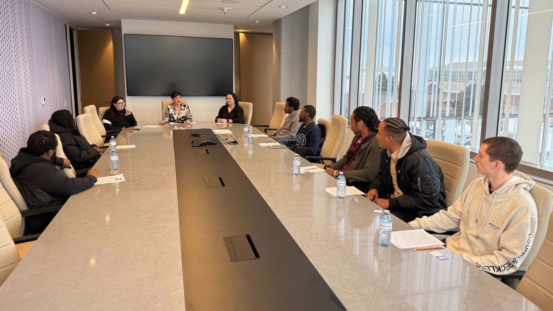 A group of people are sitting at a long table in a conference room.