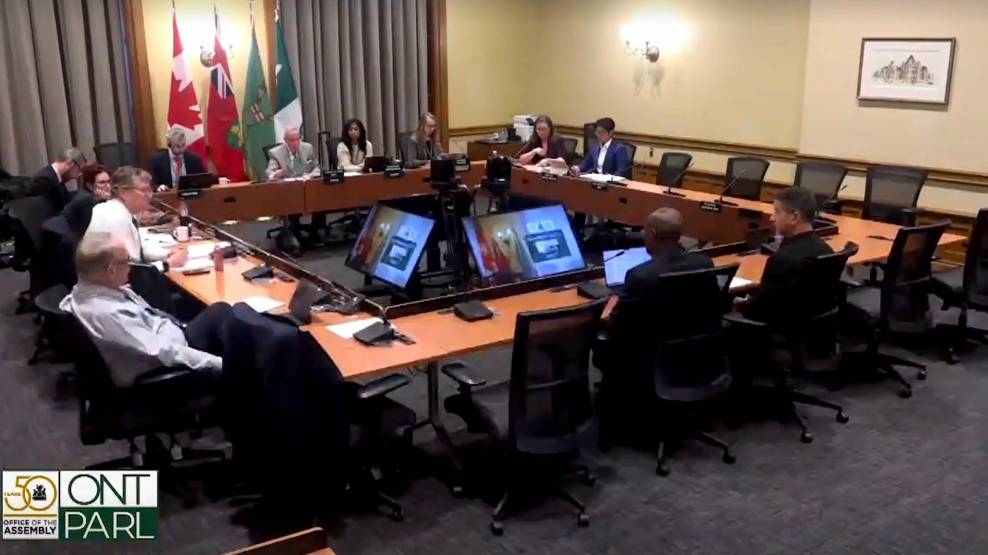 A group of people are sitting around a long table in a conference room.