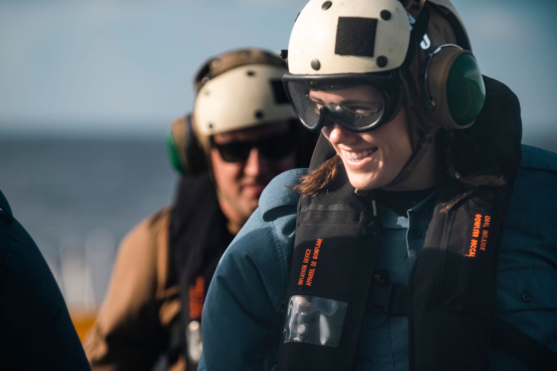 A woman wearing a helmet and goggles is sitting next to a man wearing headphones.