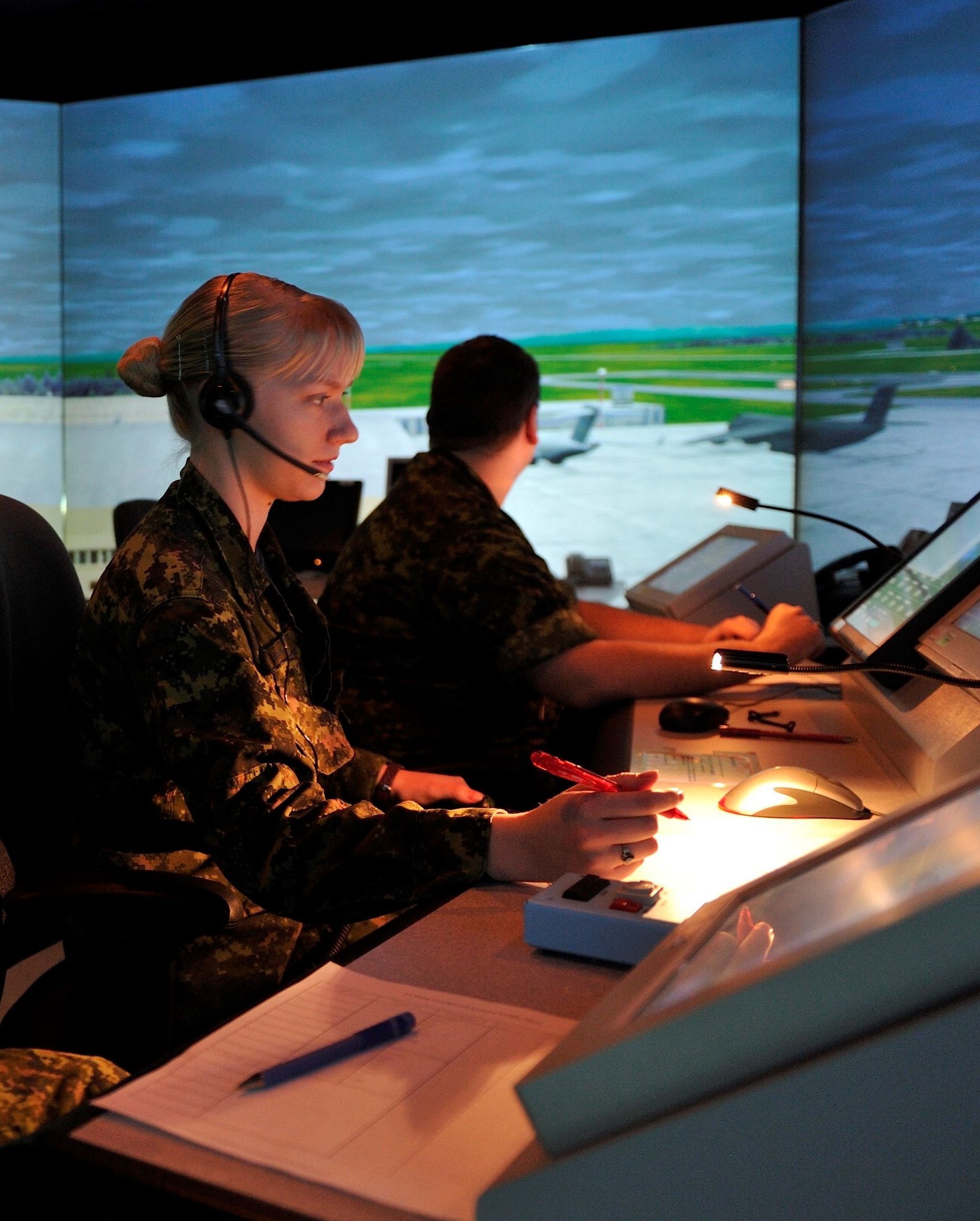 A woman wearing a headset is sitting at a desk