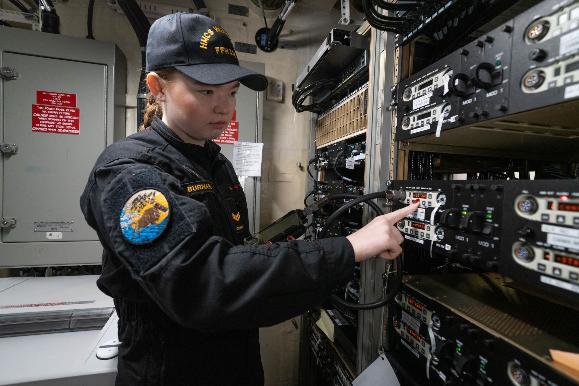 A woman in a black uniform is working on a machine in a room.