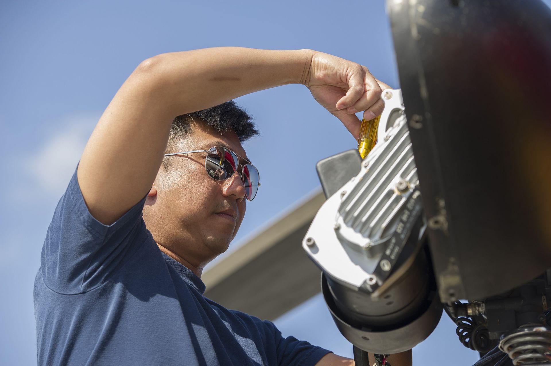 A man in a blue shirt is working on a machine.