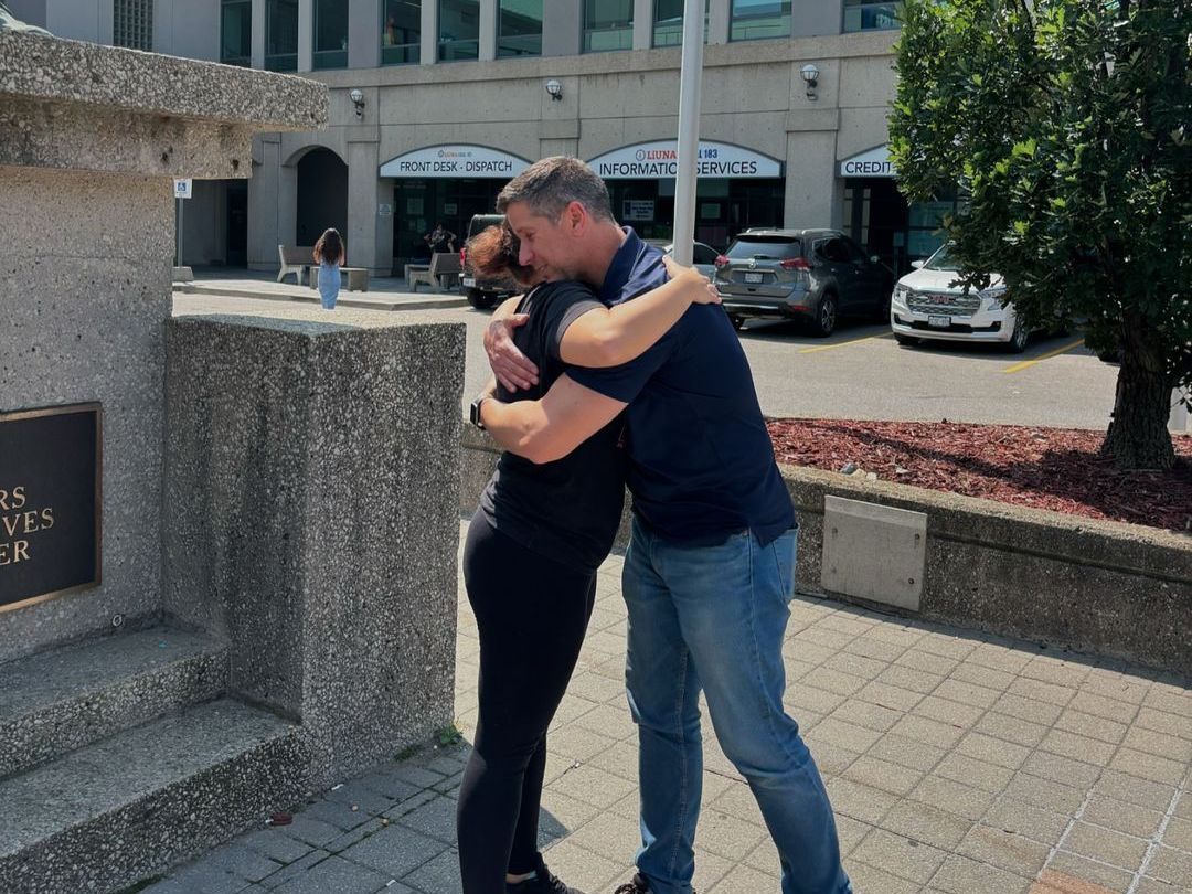 A man is hugging a woman in front of a building