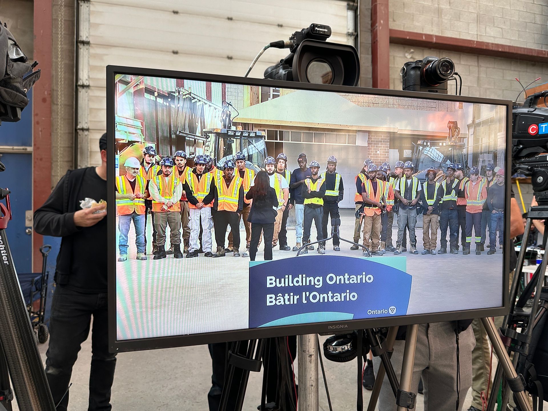 A group of construction workers are standing in front of a large screen.