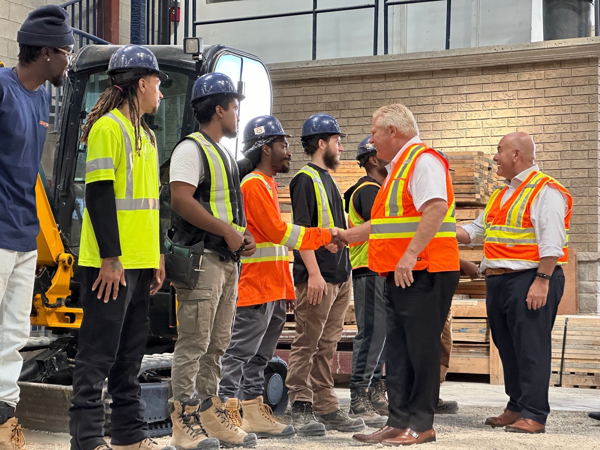 A group of construction workers are shaking hands with a man.