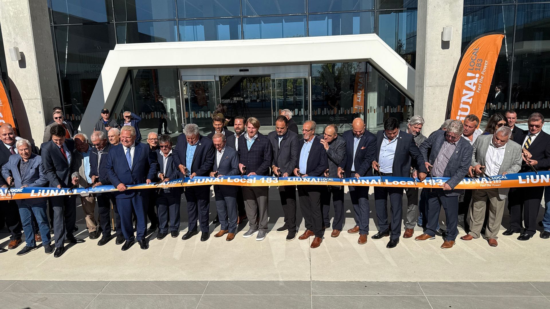 A group of men are standing in front of a building holding ribbons