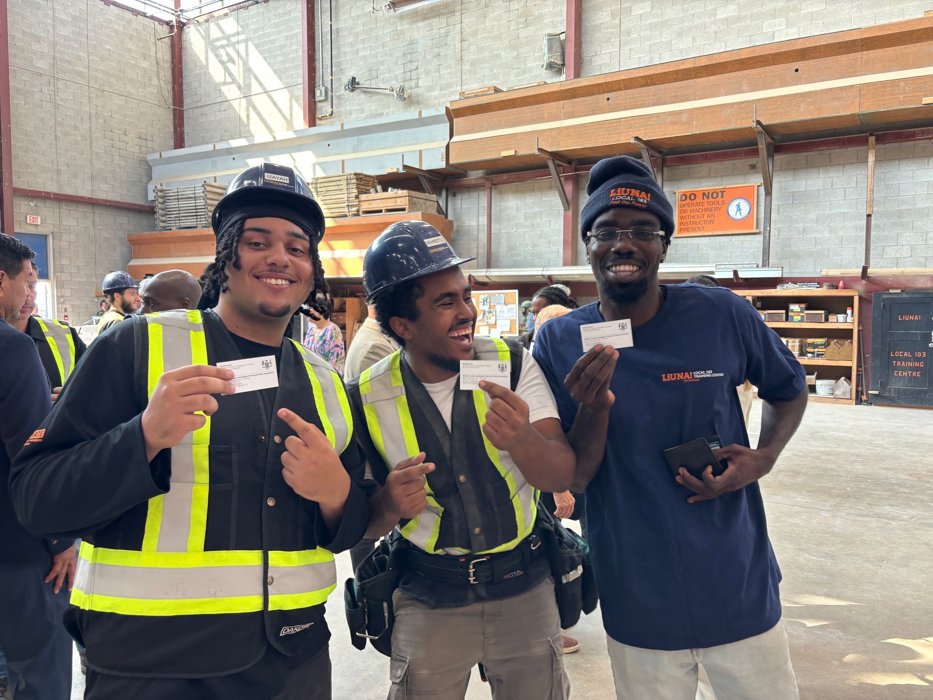 Three construction workers are posing for a picture in a warehouse.