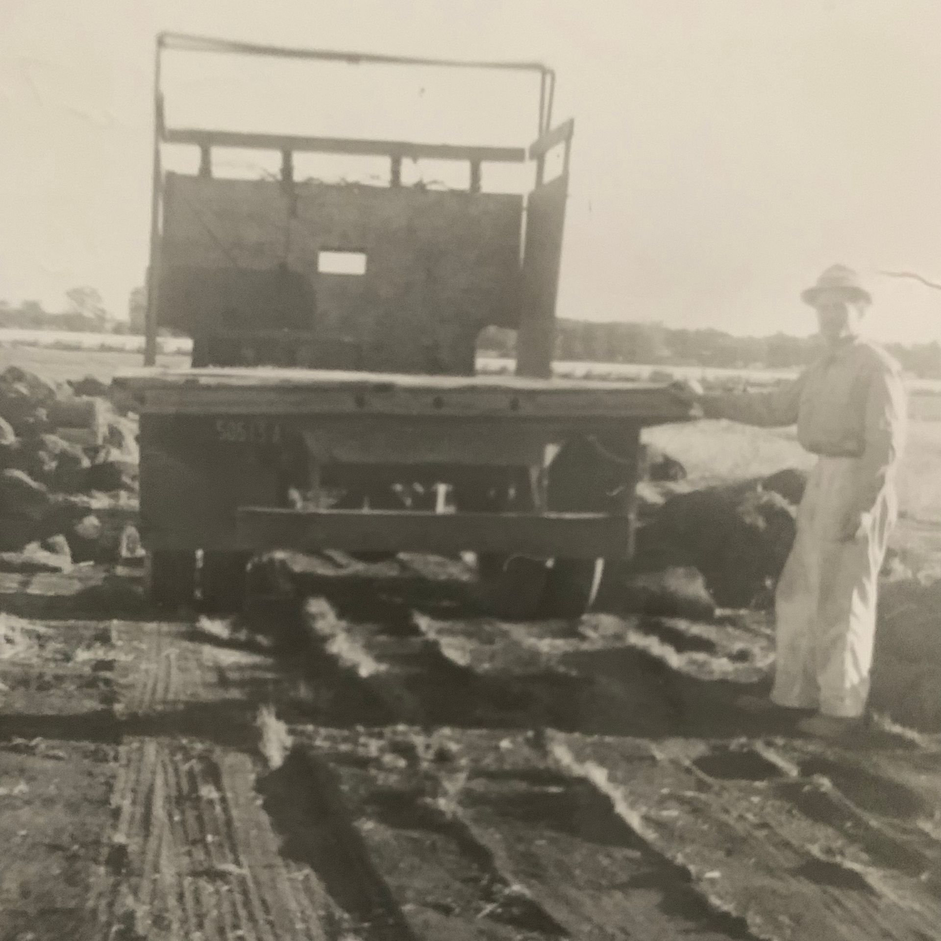 A black and white photo of a man standing in front of a truck