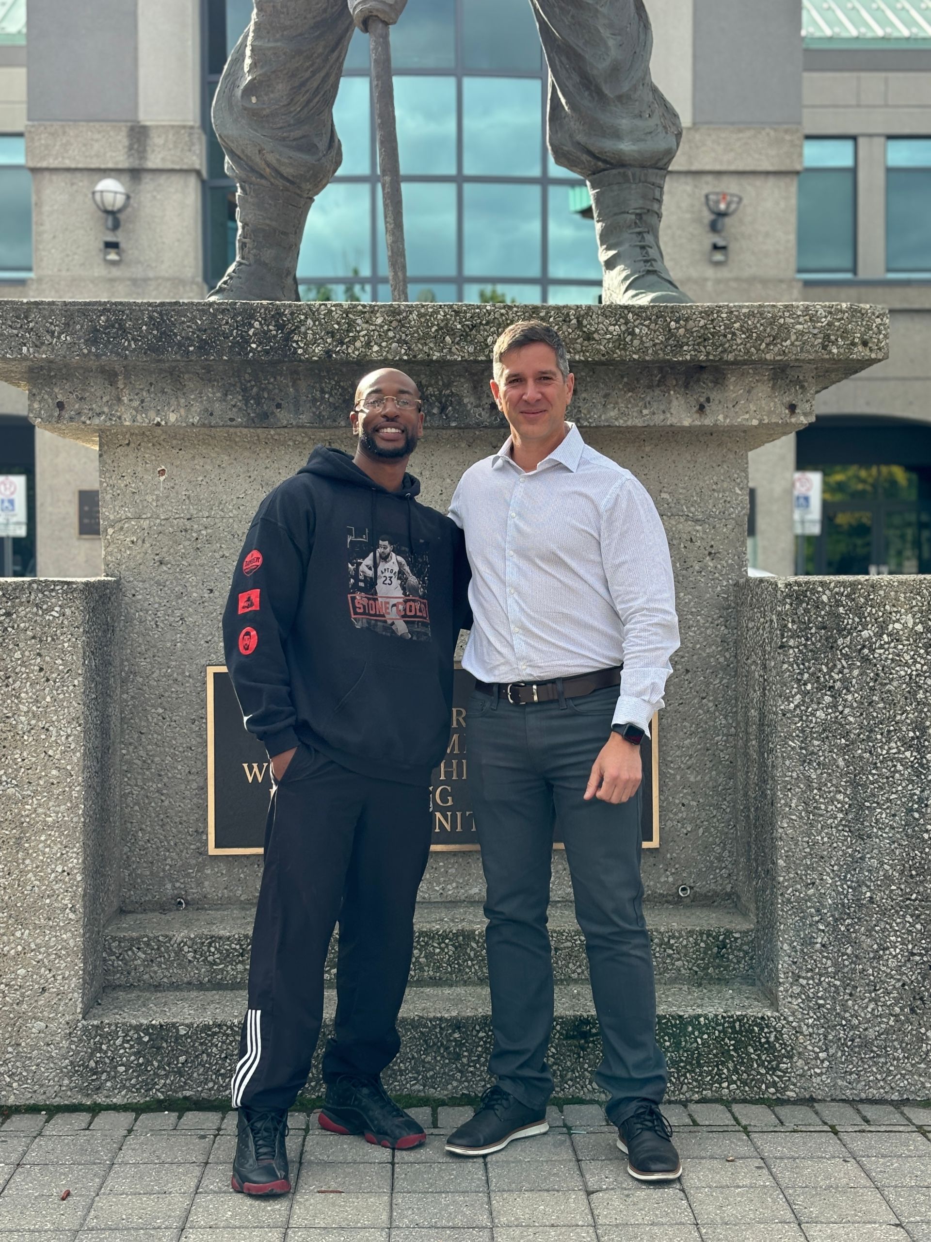 Two men are posing for a picture in front of a statue.