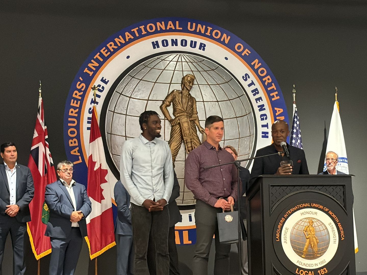 A group of men are standing in front of a podium in front of a logo for the international union of North America.