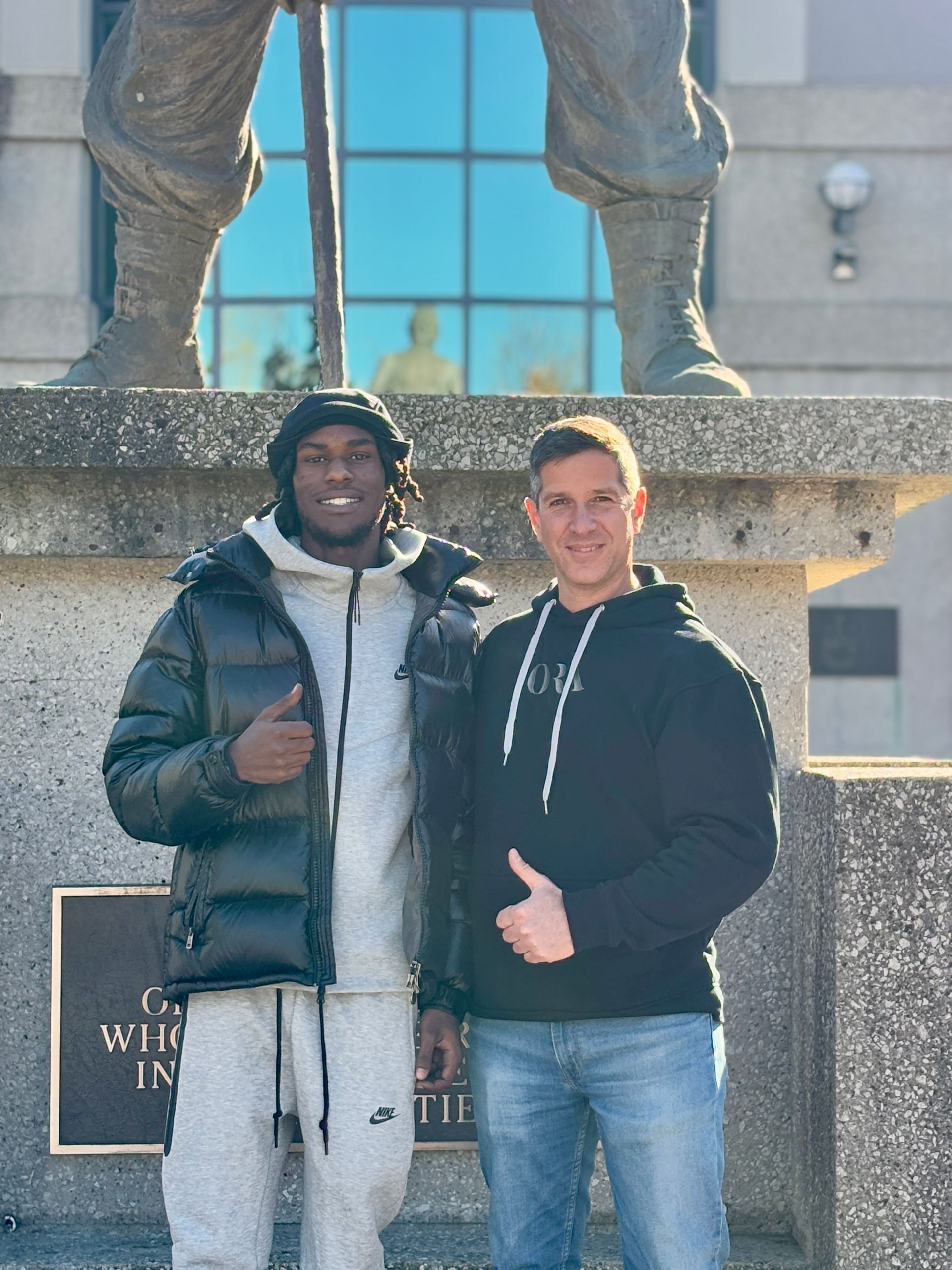 Two men are posing for a picture in front of a statue.