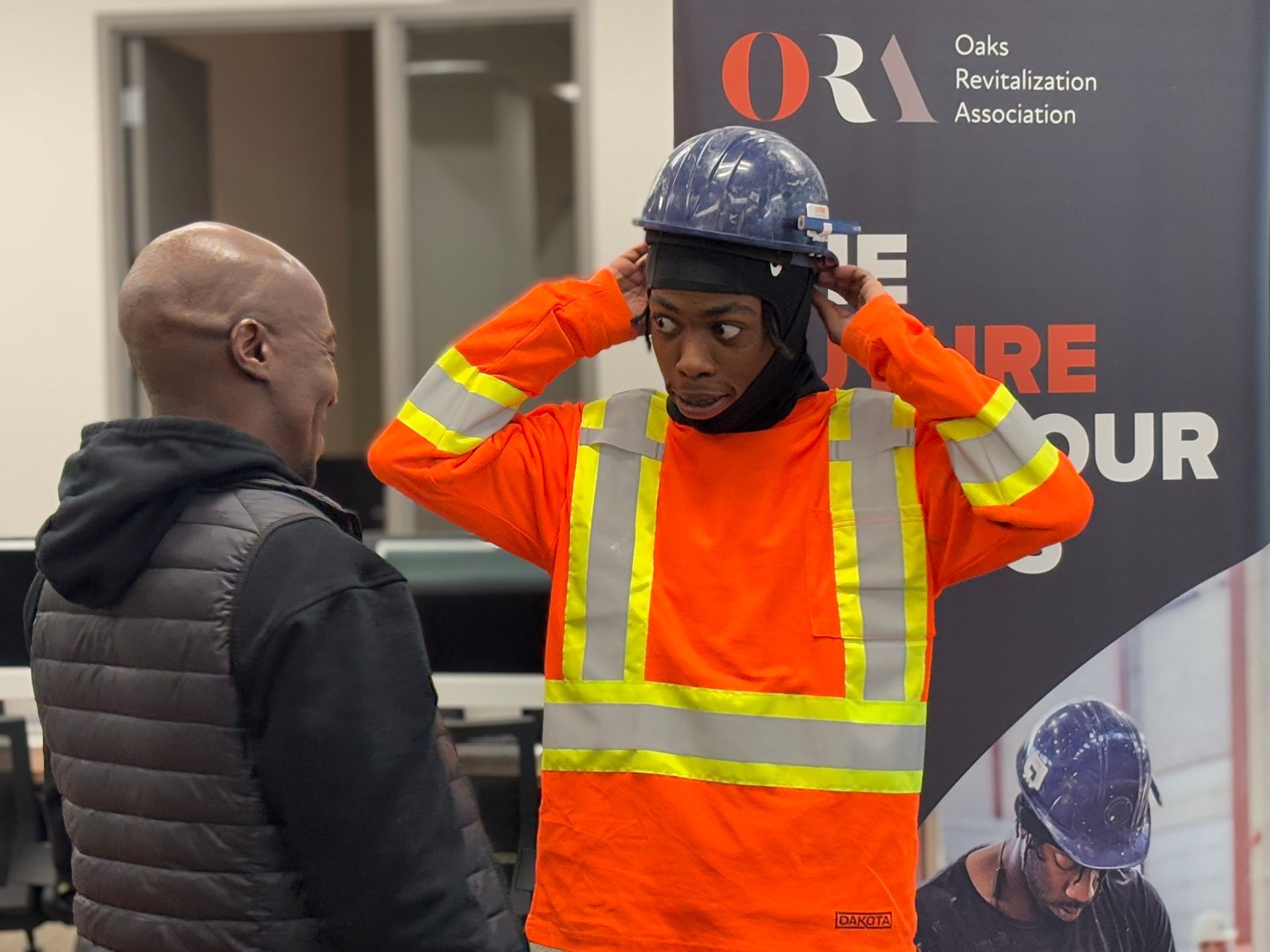 A man wearing a hard hat is talking to another man.