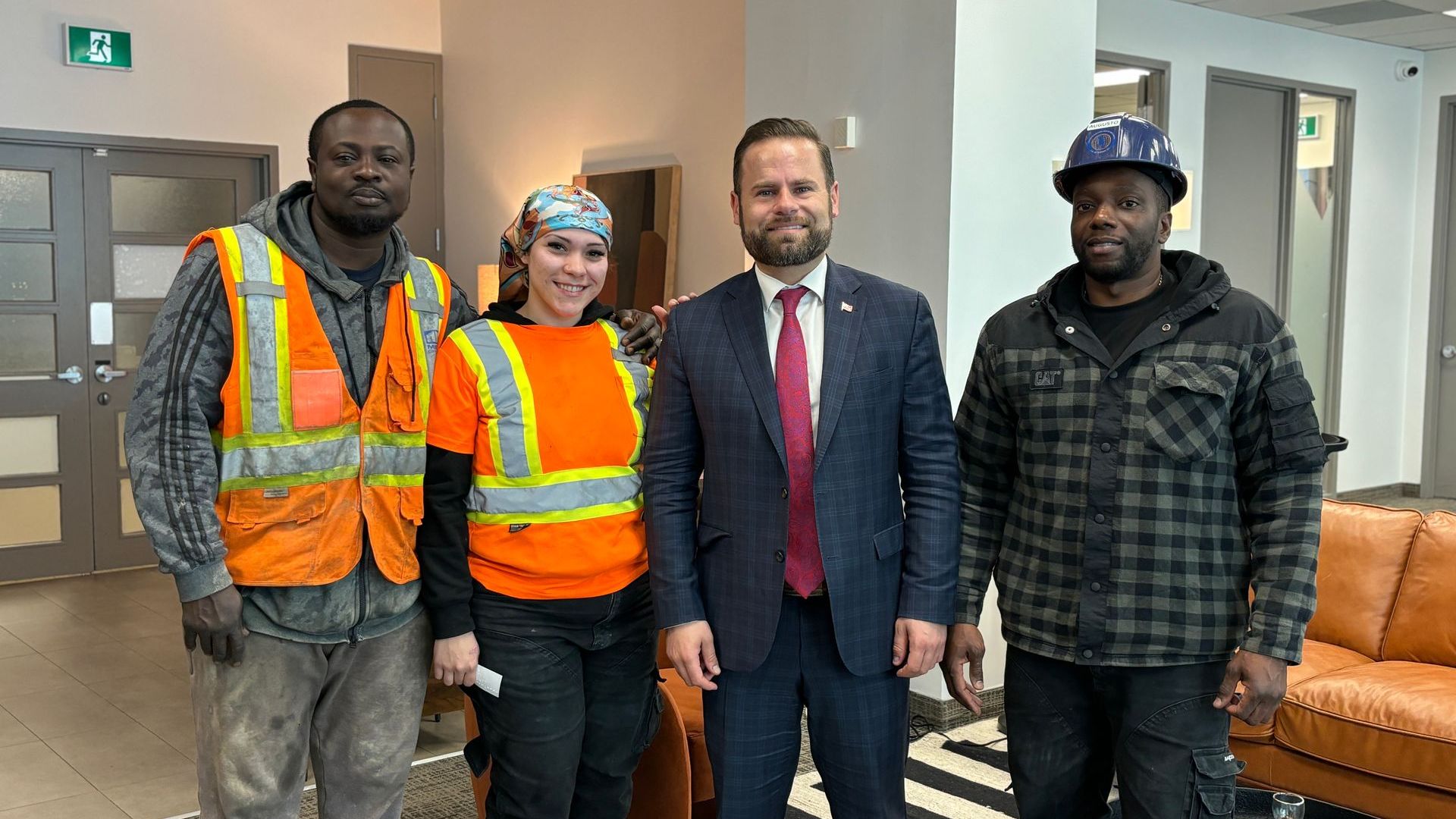 A group of construction workers are posing for a picture with a man in a suit.