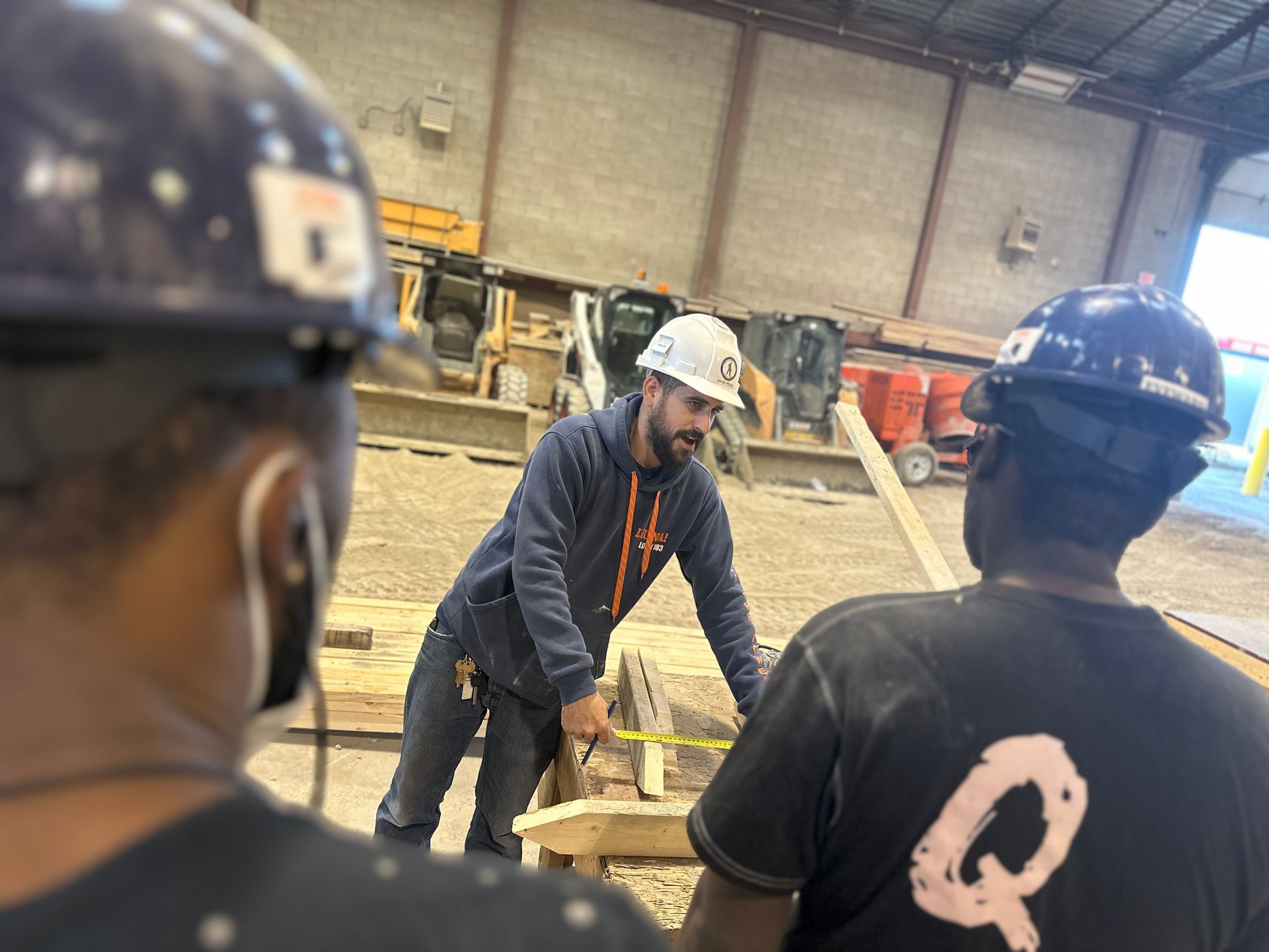 a man wearing a hard hat is measuring a piece of wood