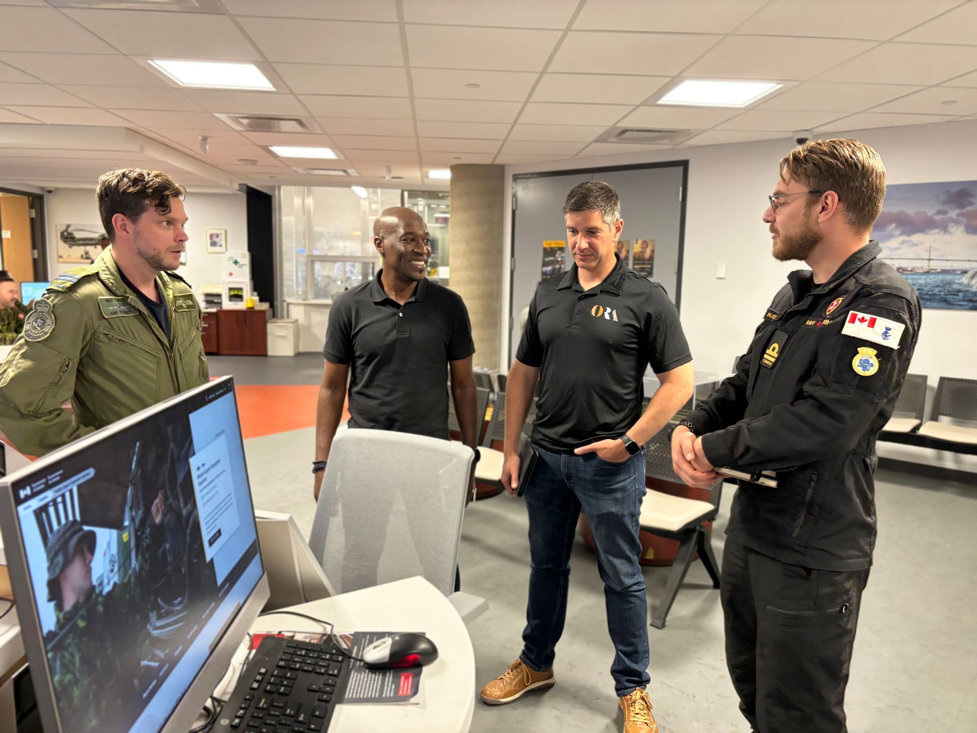 A group of men are standing around a computer in a room.