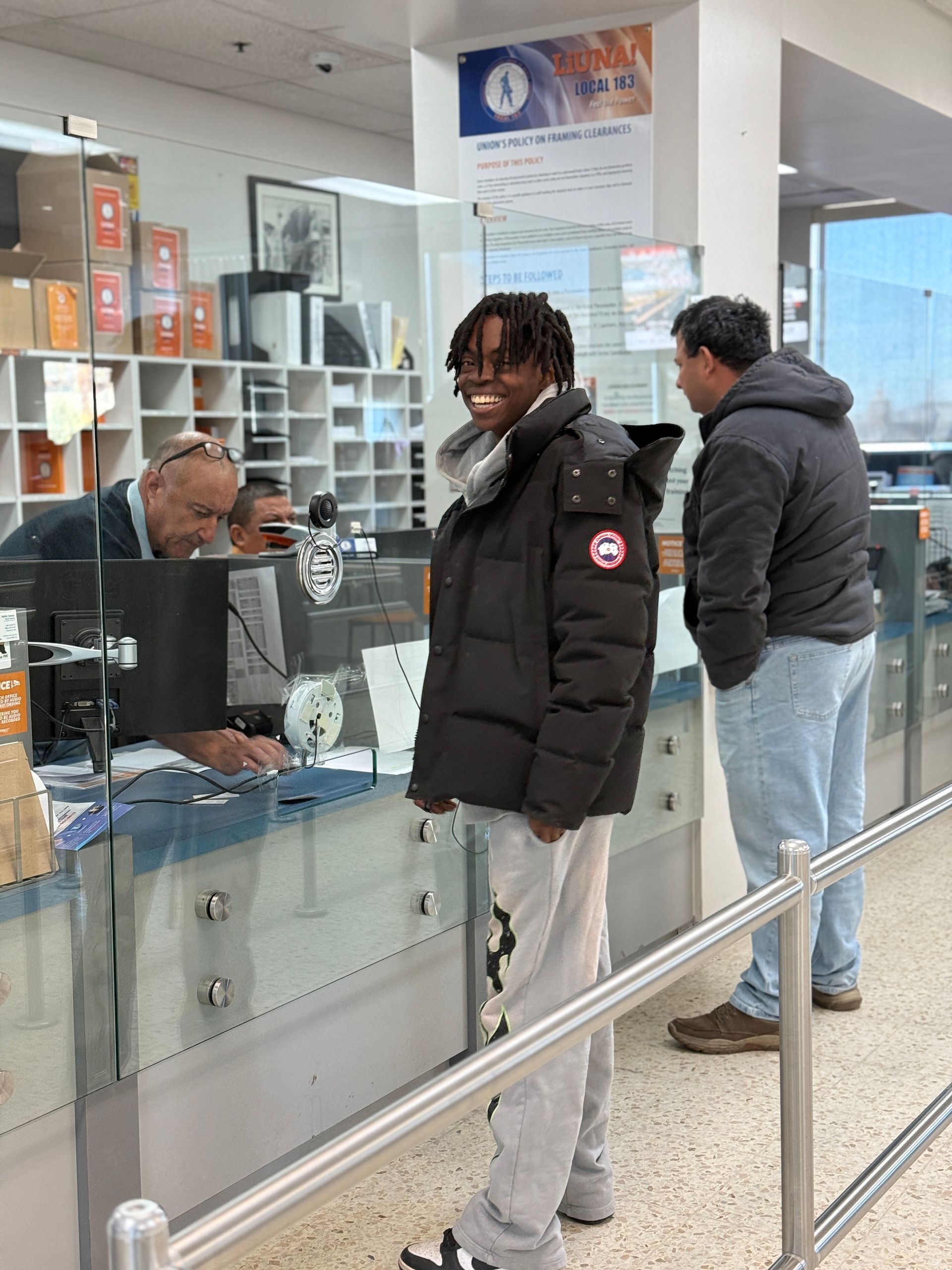 A man in a black jacket is standing in front of a counter at a post office