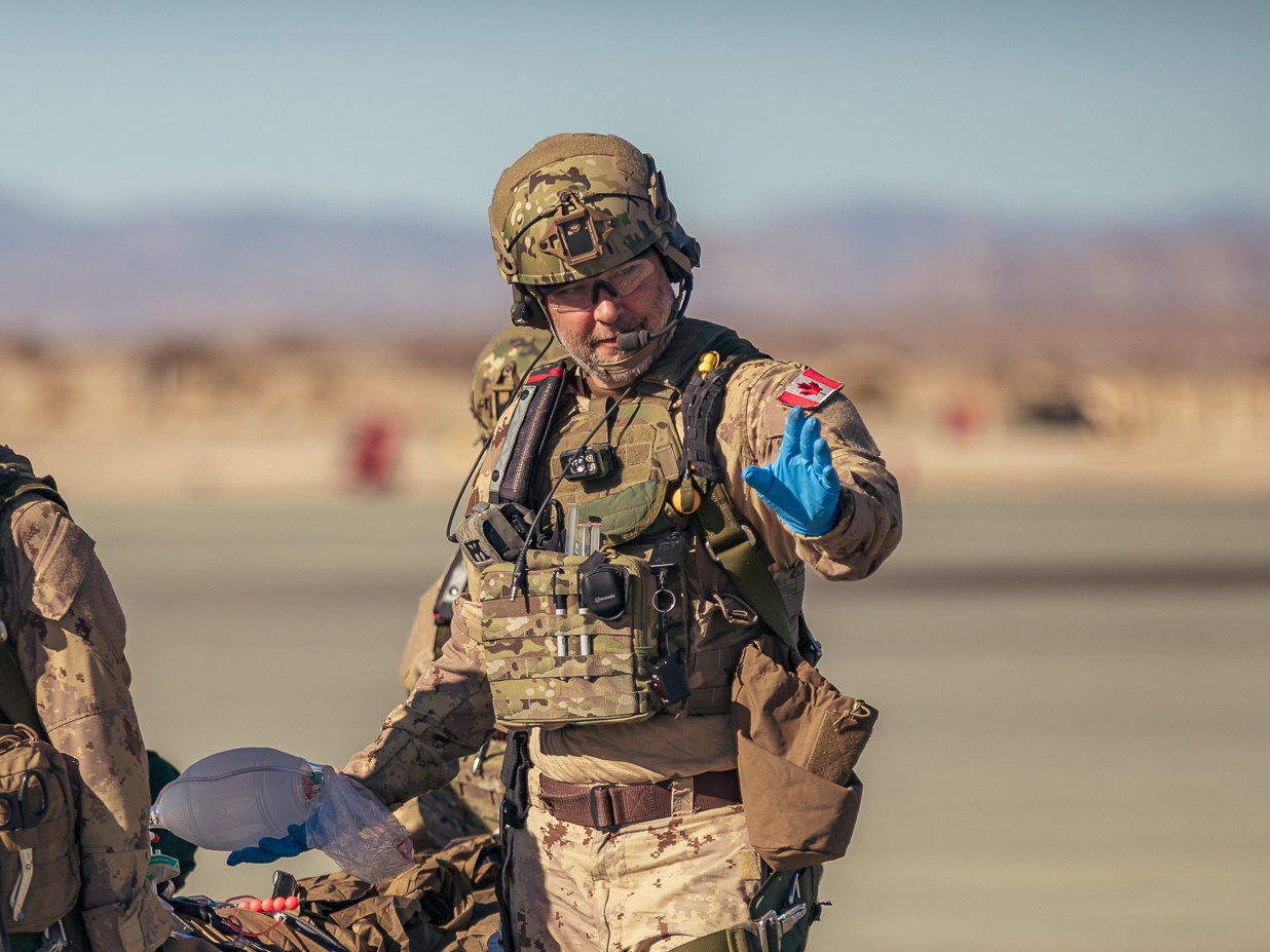 A soldier is carrying a stretcher in the desert.