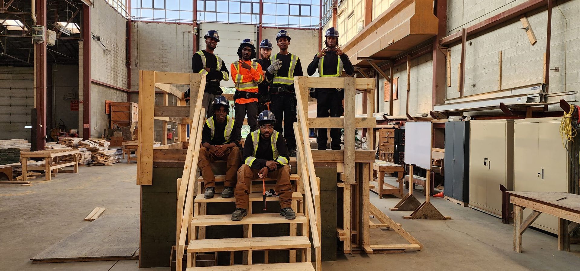 A group of construction workers are posing for a picture in a warehouse.