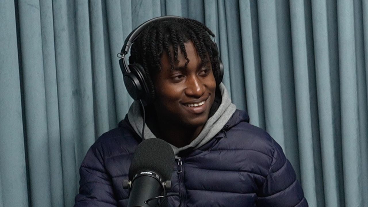 A man wearing headphones is sitting in front of a microphone.