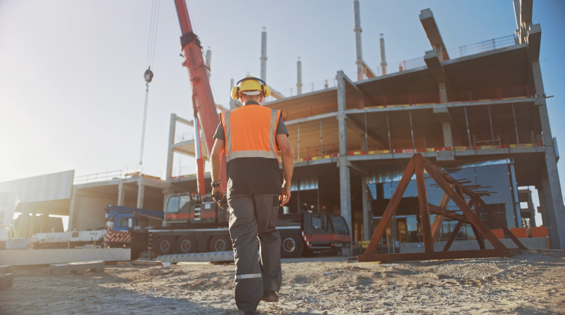 a construction worker is walking towards a large building under construction .
