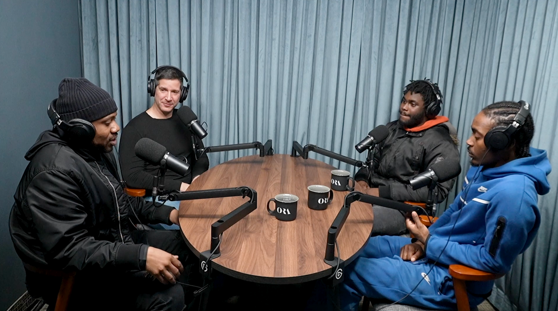 A group of people are sitting around a table with microphones.