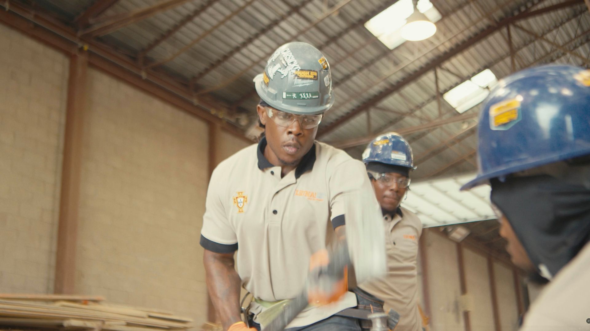 A group of men wearing hard hats and safety glasses are working in a warehouse.