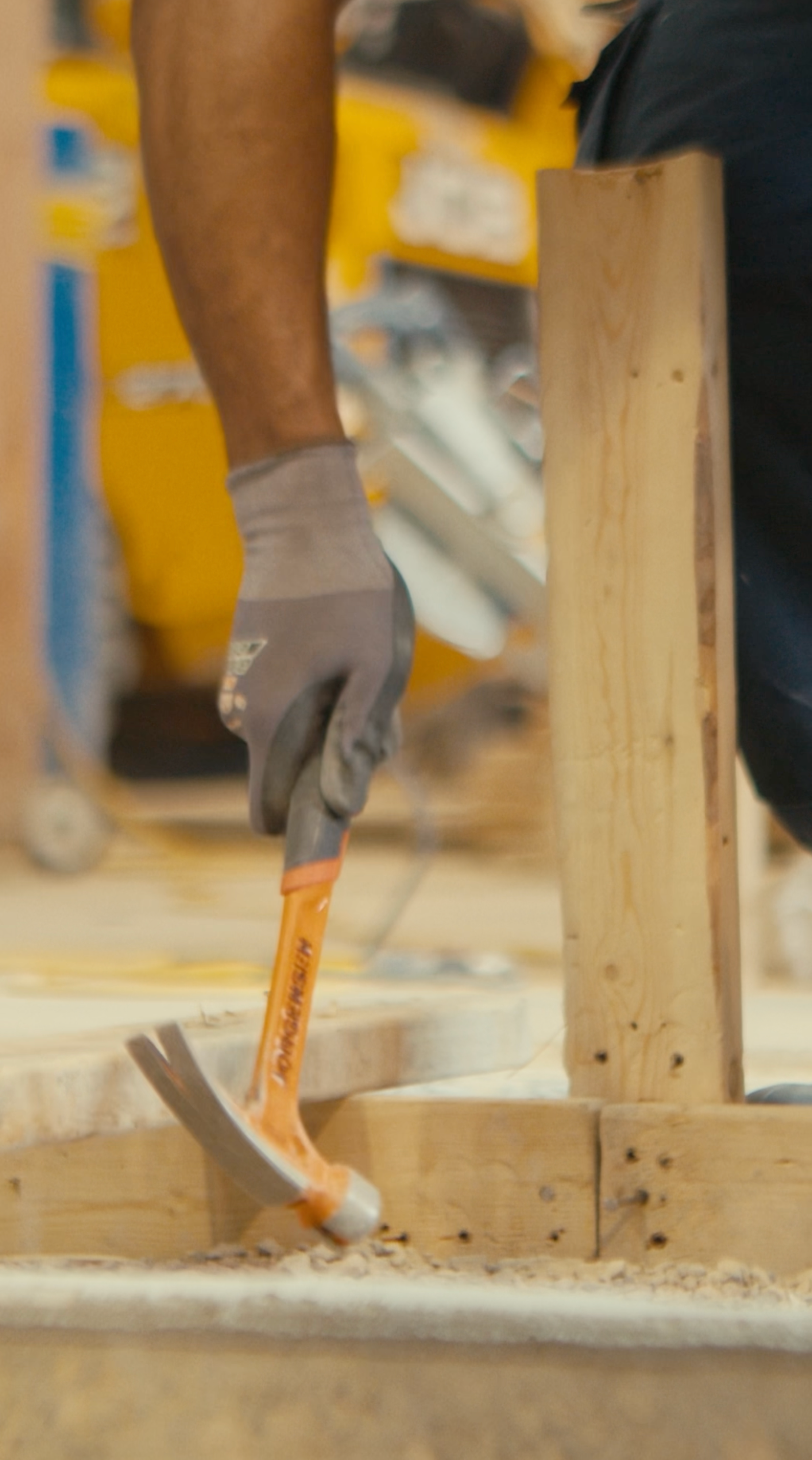 A man is using a hammer to hammer a piece of wood.