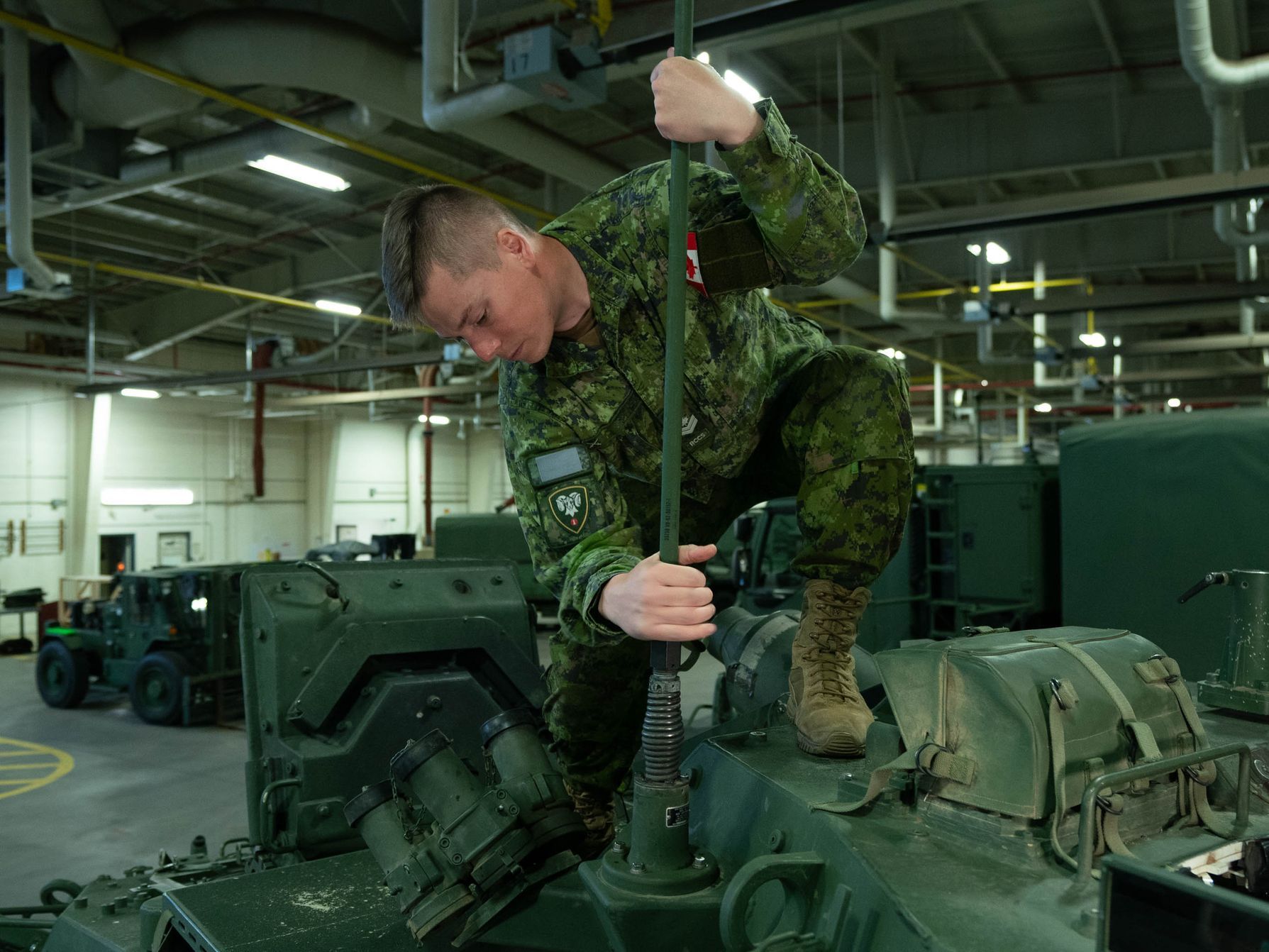 A soldier is working on a tank in a garage.