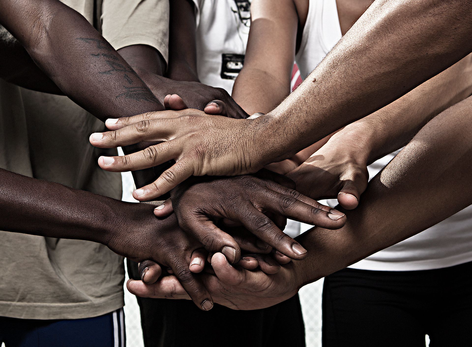 Hands of various skin tones clasped together in a symbol of unity.