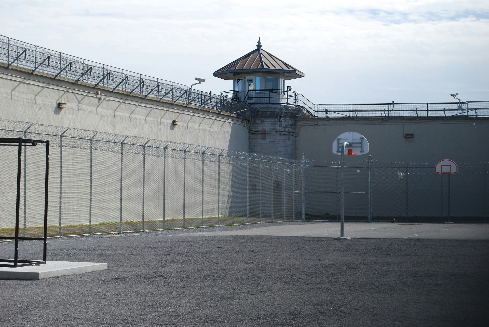 a prison yard with a barbed wire fence and a tower in the background