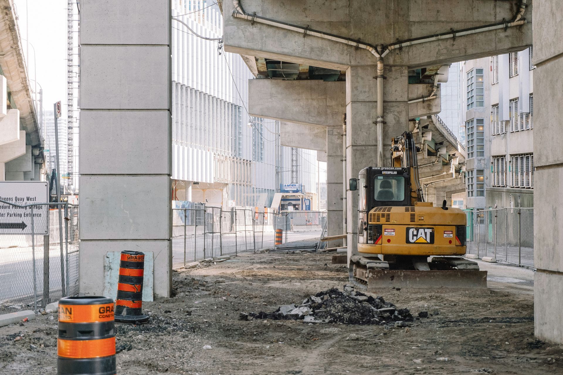 A cat excavator is sitting under a bridge.