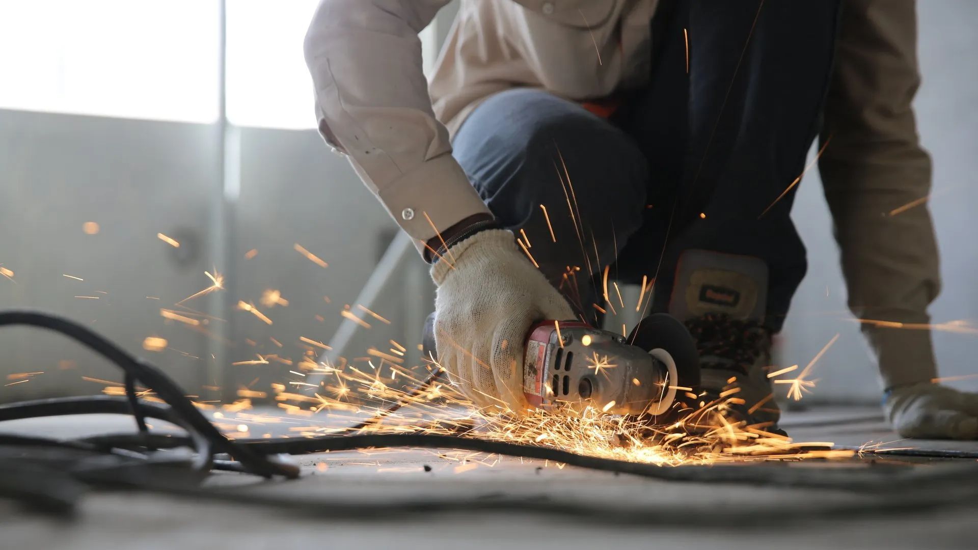 A man is using a grinder to cut a piece of metal.
