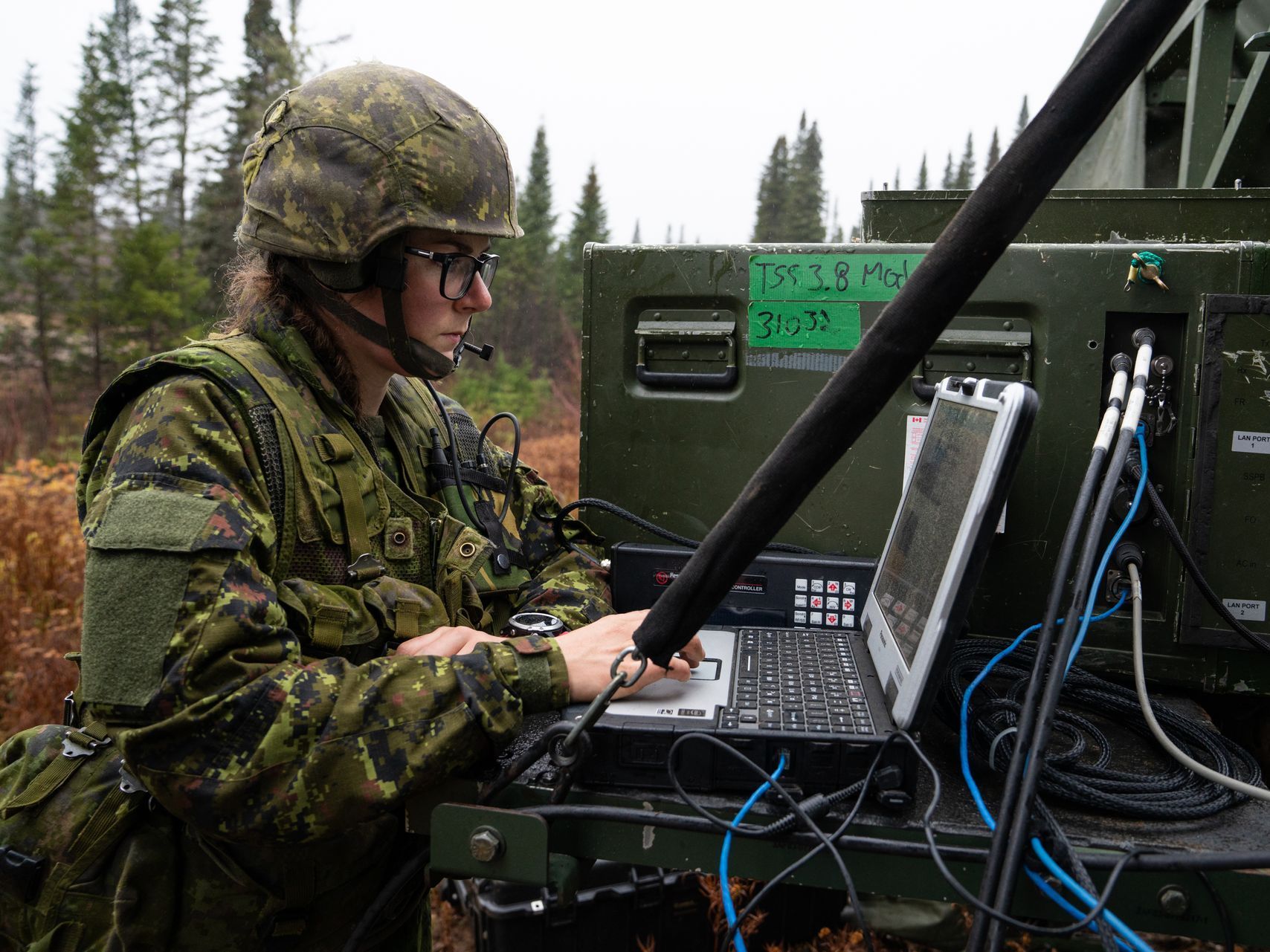 A woman in a military uniform is using a laptop