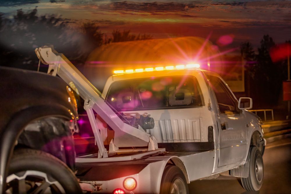 A Tow Truck is Towing a Car on the Side of the Road at Night — Mareeba Express Towing in Innisfail, QLD