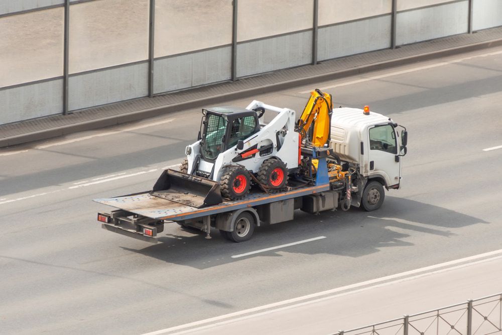 A Tow Truck is Carrying a Bulldozer on the Back of It — Mareeba Express Towing in Mareeba, QLD