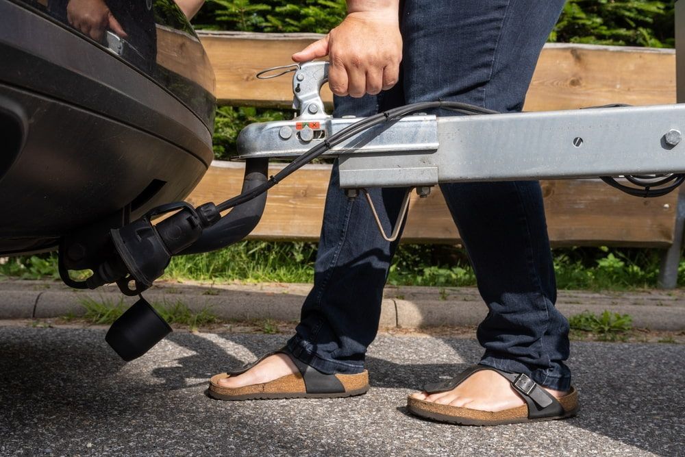 A Person is Attaching a Trailer to the Back of a Car — Mareeba Express Towing in Mareeba, QLD