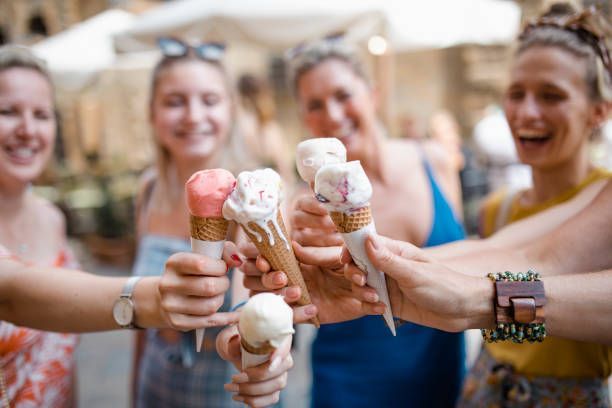 A group of women are holding ice cream cones in their hands.