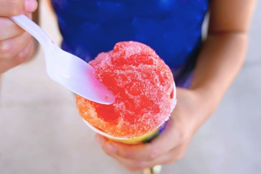 A person is eating a cup of shaved ice with a spoon.