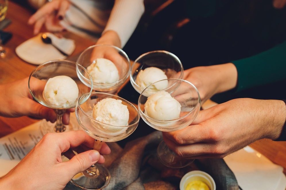 A group of people are toasting with ice cream in champagne glasses.