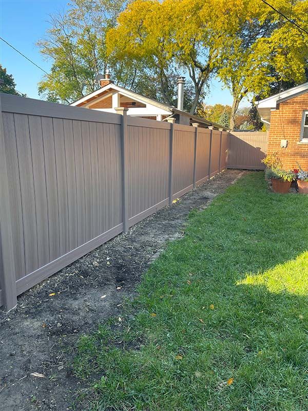 A wooden gate is between two buildings on a sidewalk.