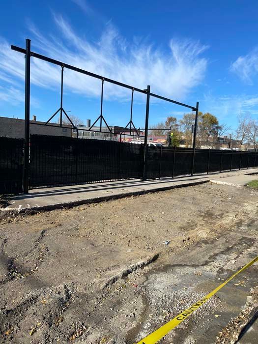 A black fence is surrounding a dirt road